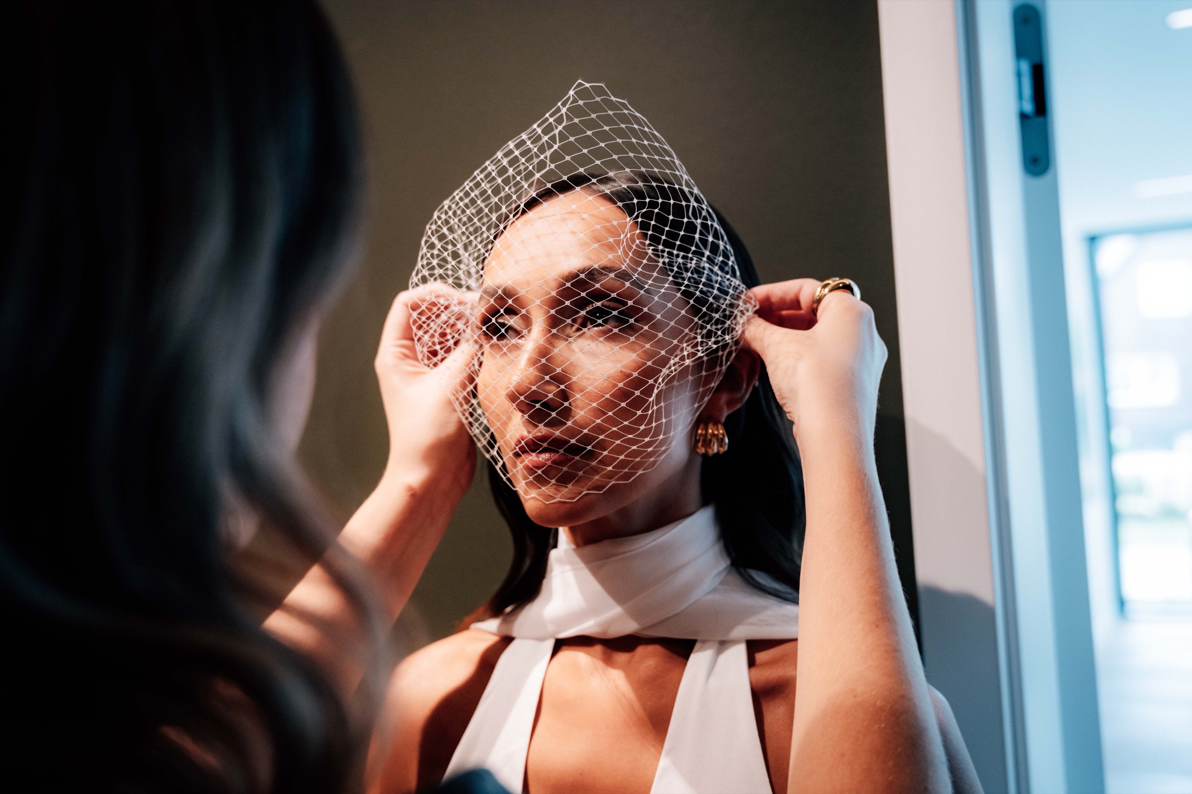 Braut richtet ihren Birdcage-Schleier, Editorial-Aufnahme im Gegenlicht
