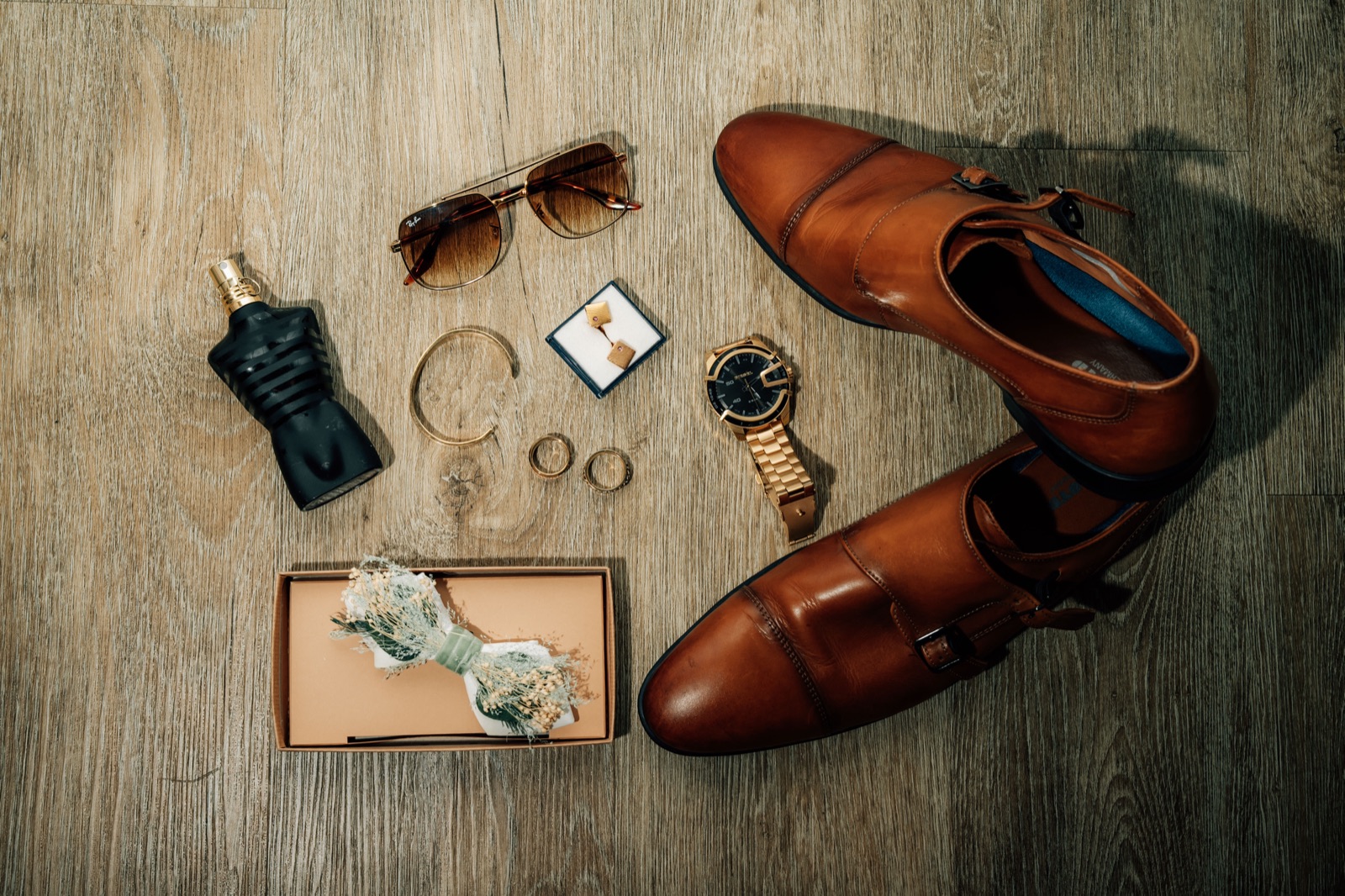 Flatlay des Bräutigams: Uhr, Sonnenbrille, Parfum, Monkstraps
